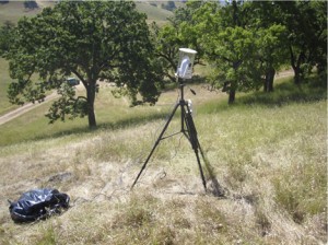 Snakes in the Grass 3 white webcam beneath a clear plastic dome mounted atop a tripod in an oak grassland.